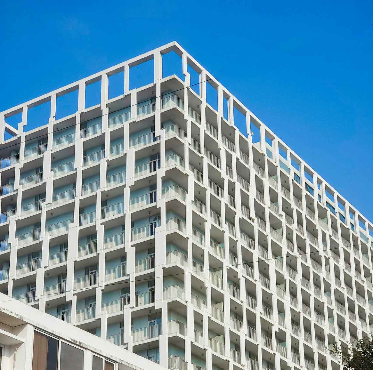 A tall white building with balconies on top of it.