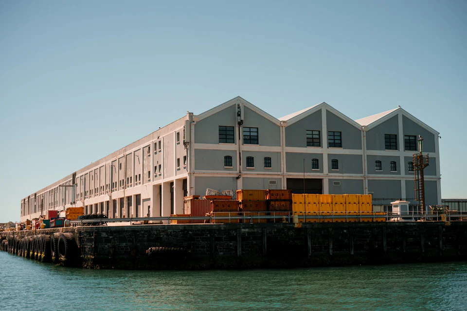 Long warehouse building on a pier with stacks of boxes.