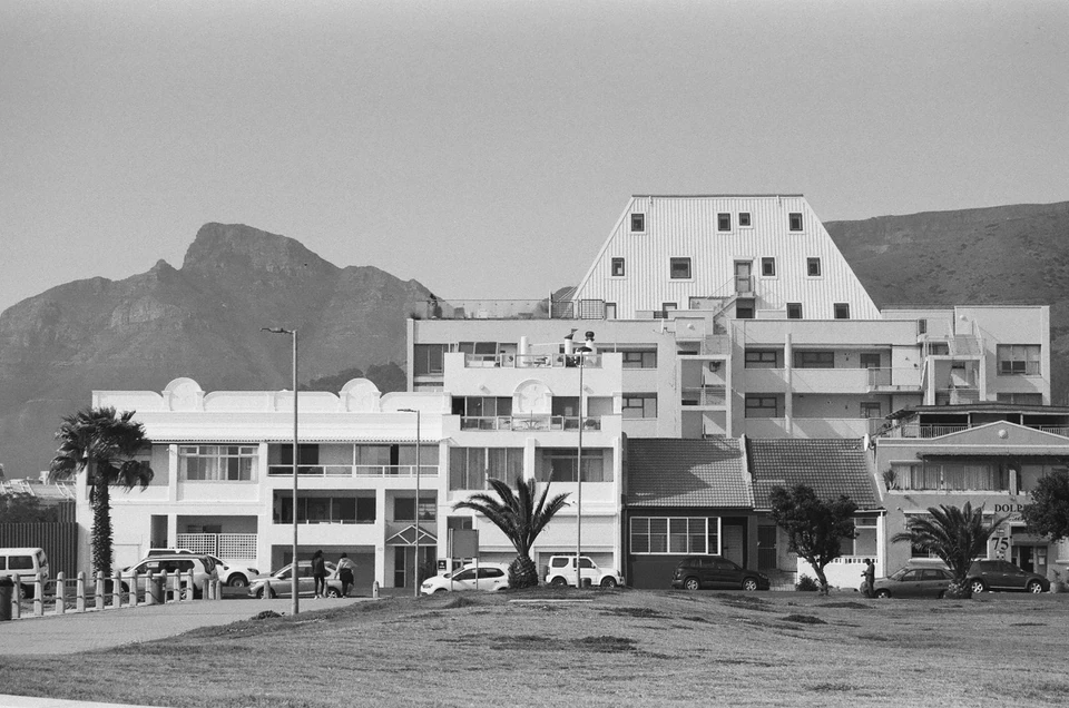 A black and white photo of a building with mountains in the background.