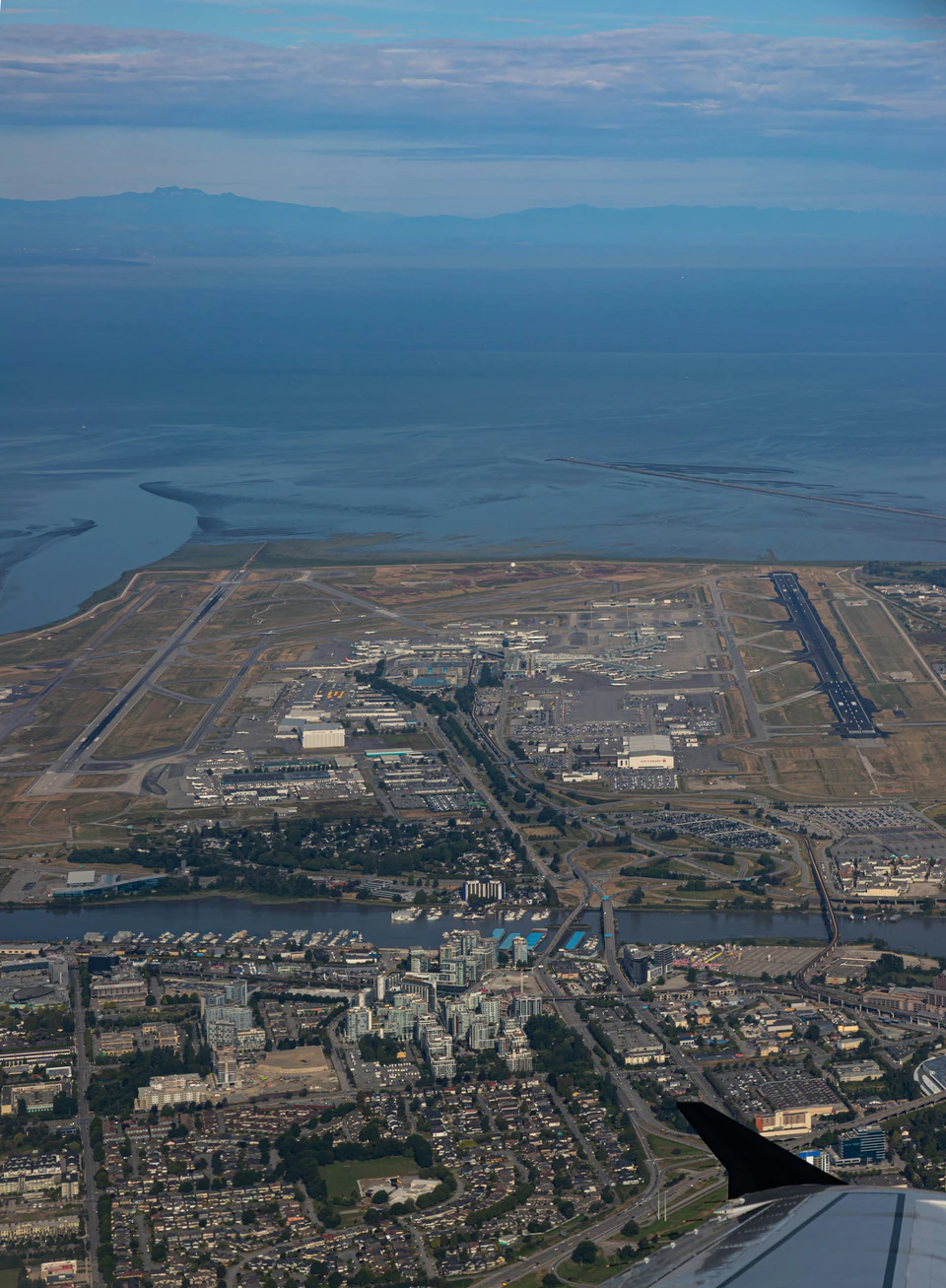 Aerial view of a large airport and coastal city.