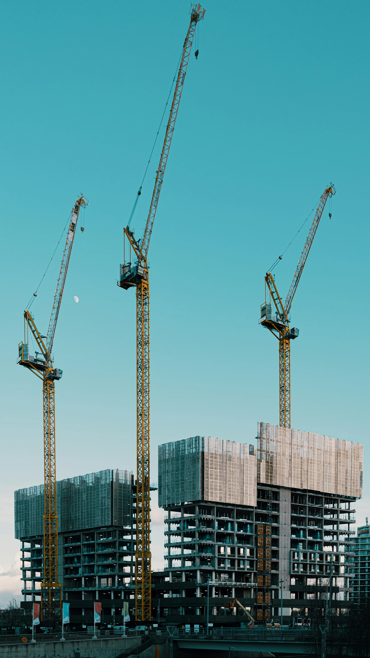 A group of cranes standing on top of a building under construction.