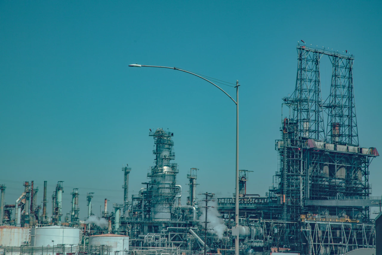 Industrial oil refinery complex under a clear blue sky.