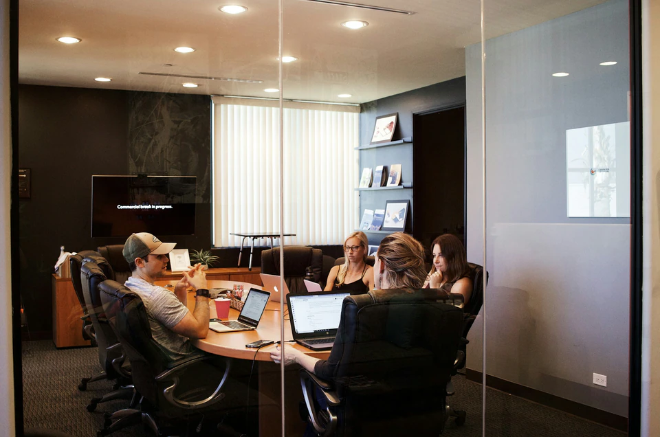 People sitting near table with laptop computer.