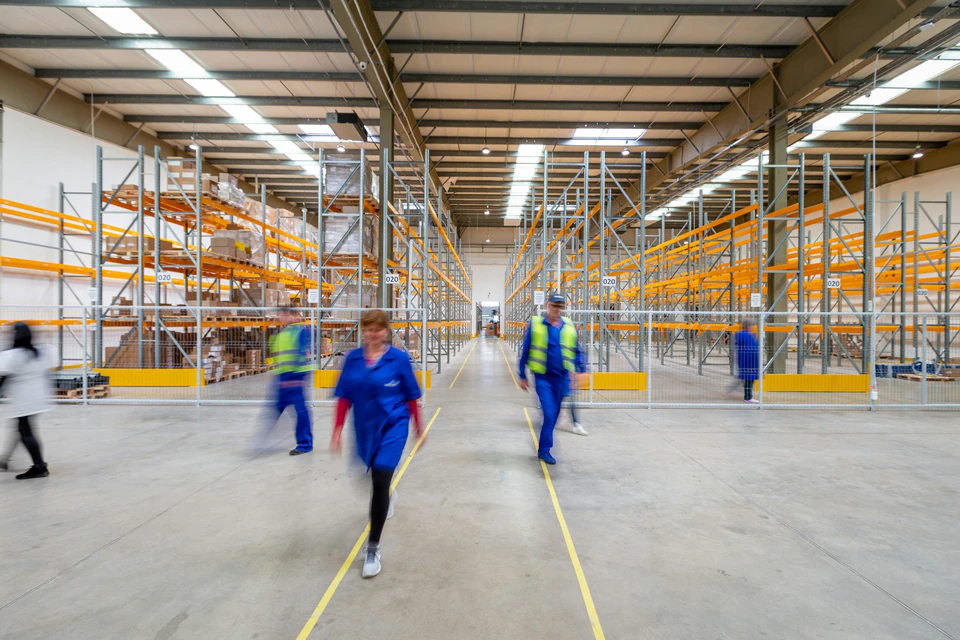 Workers walking through warehouse aisle.