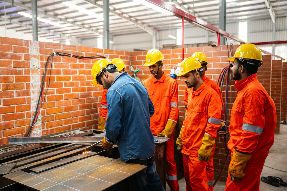 Workers in hard hats and safety vests in a workshop.